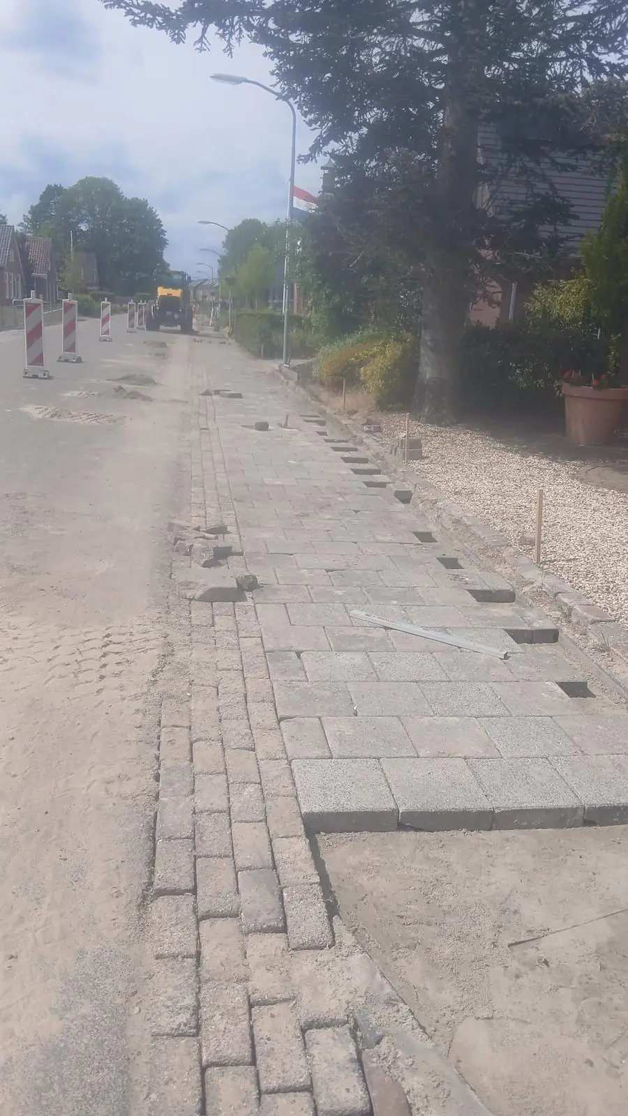 Trottoir dat opnieuw wordt bestraat, klinkers strak op hoogte langs de band